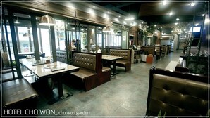 Un ristorante con sedute a cabina e tavoli, ampie finestre e lampade a sospensione.