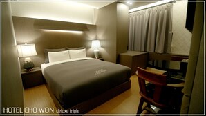 Una camera d'albergo con un letto grande, lampade sui comodini, una scrivania e una sedia.