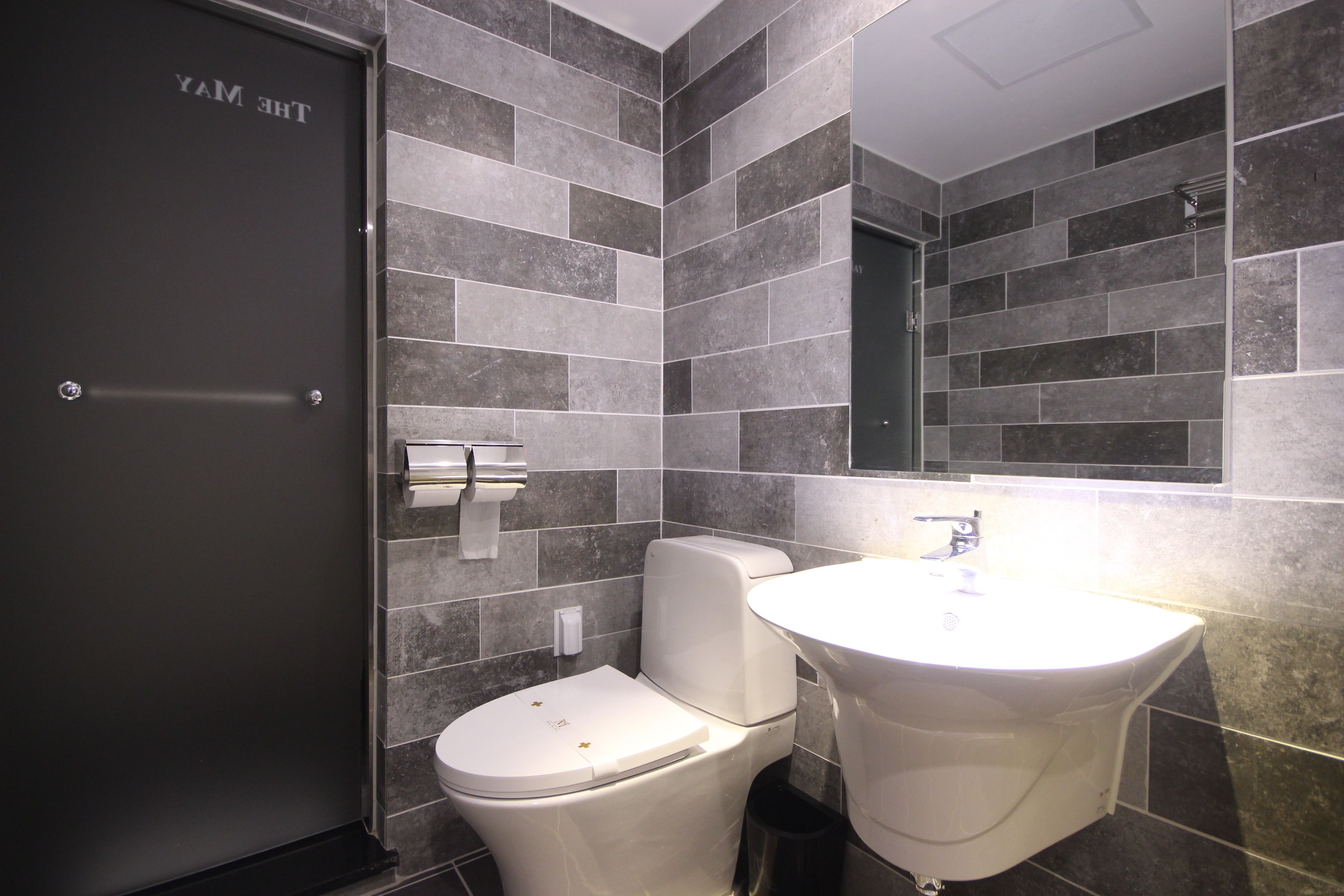 Un baño moderno con inodoro, lavabo y espejo.