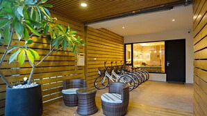 A modern interior with wooden panel walls, a row of bicycles, wicker furniture, and a potted plant. - Traveller Inn Book Haus (Taitung)