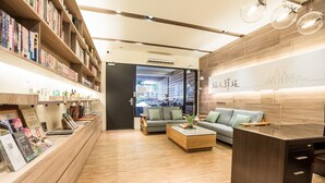 A modern interior with wooden flooring, a sofa, a coffee table, and bookshelves. - Traveller Inn Book Haus (Taitung)