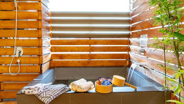 A wooden cabin with a sauna, towels, and a small plant. - Traveller Inn Book Haus (Taitung)