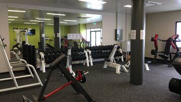 A gym with various exercise equipment, including treadmills, weight machines, and dumbbells.