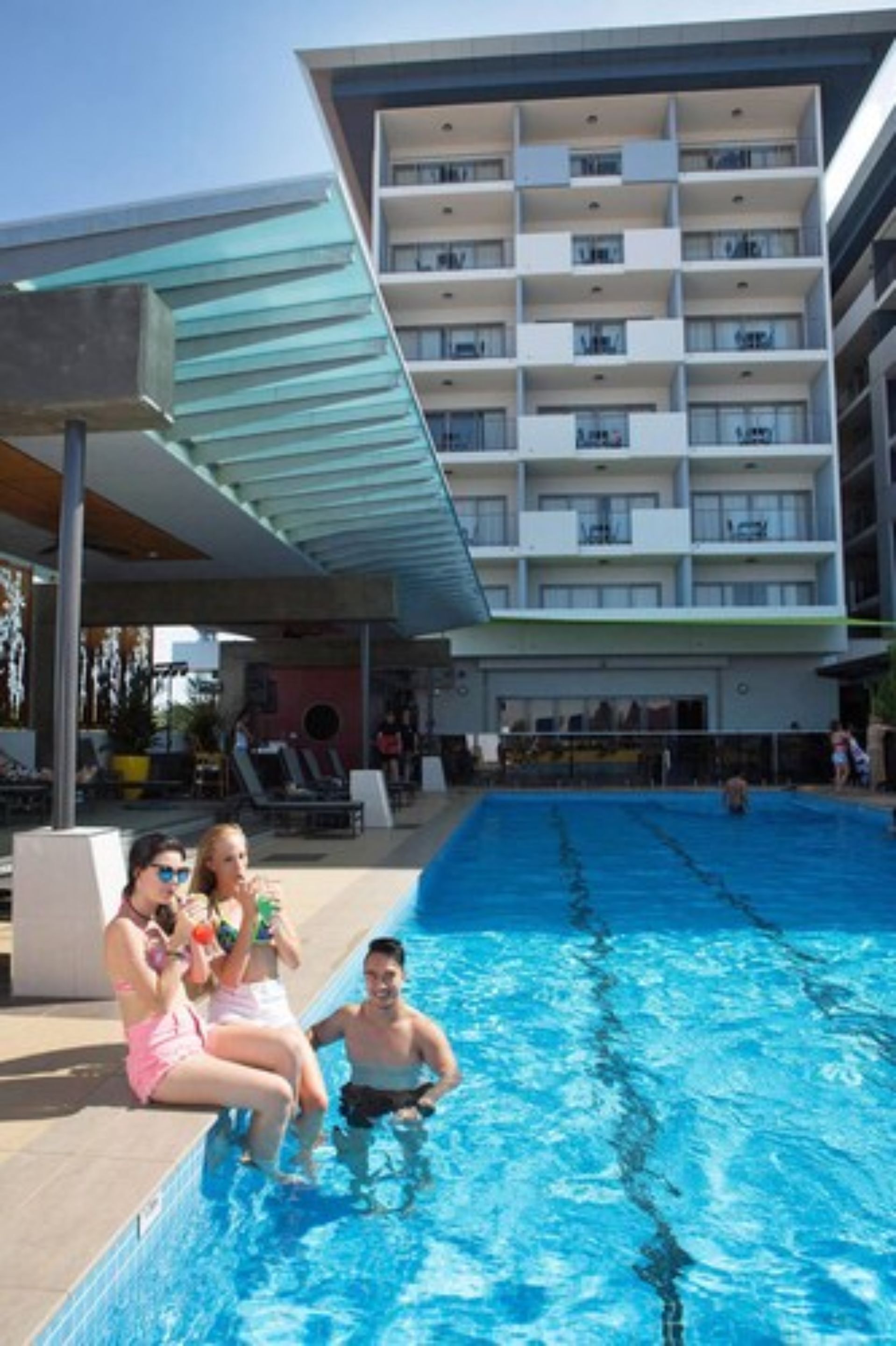 A swimming pool adjacent to a multi-story building with balconies.