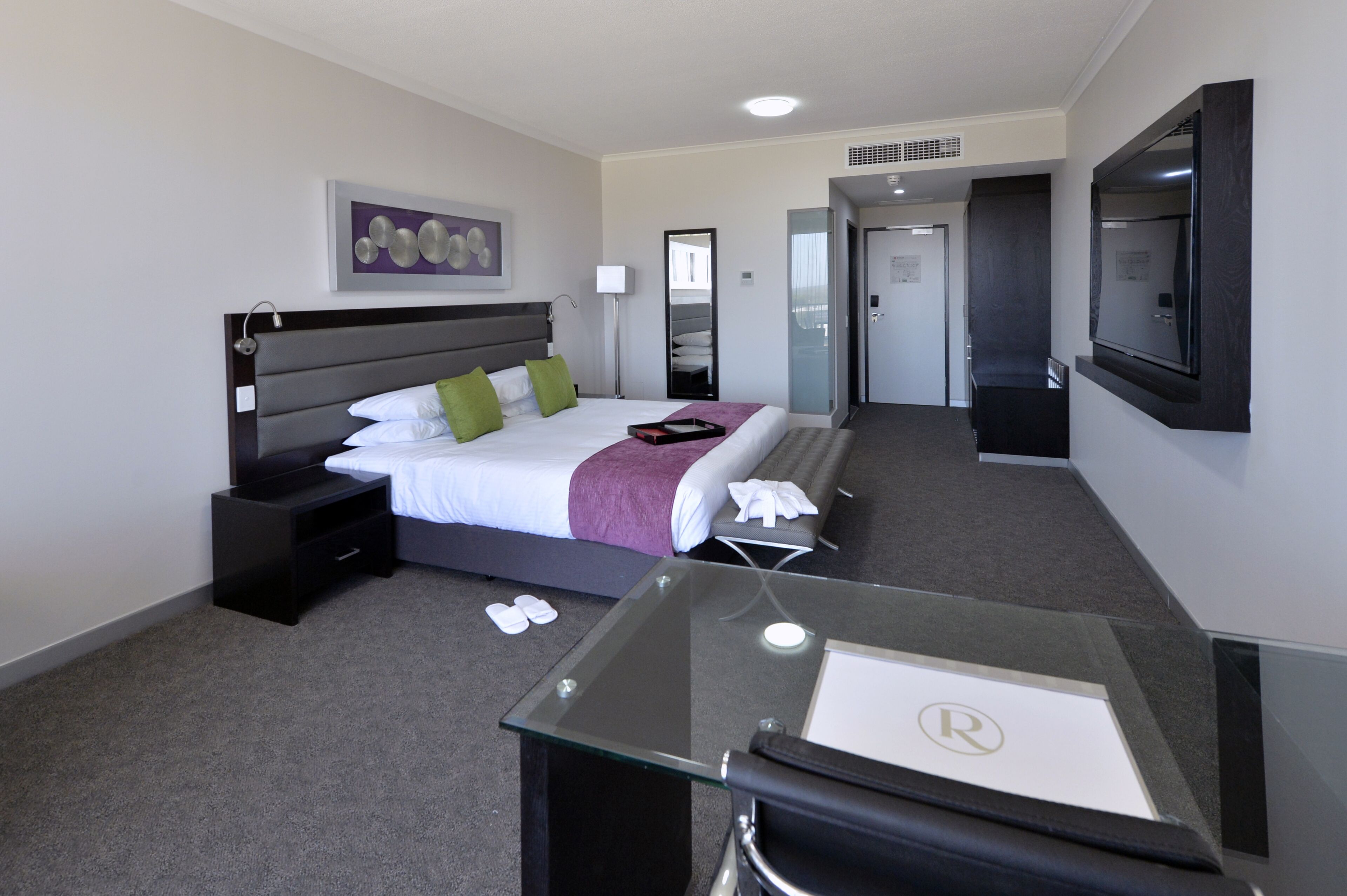 Una habitación de hotel con cama, mesita de noche y escritorio con silla.