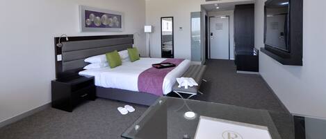Una habitación de hotel con cama, mesita de noche y escritorio con silla.