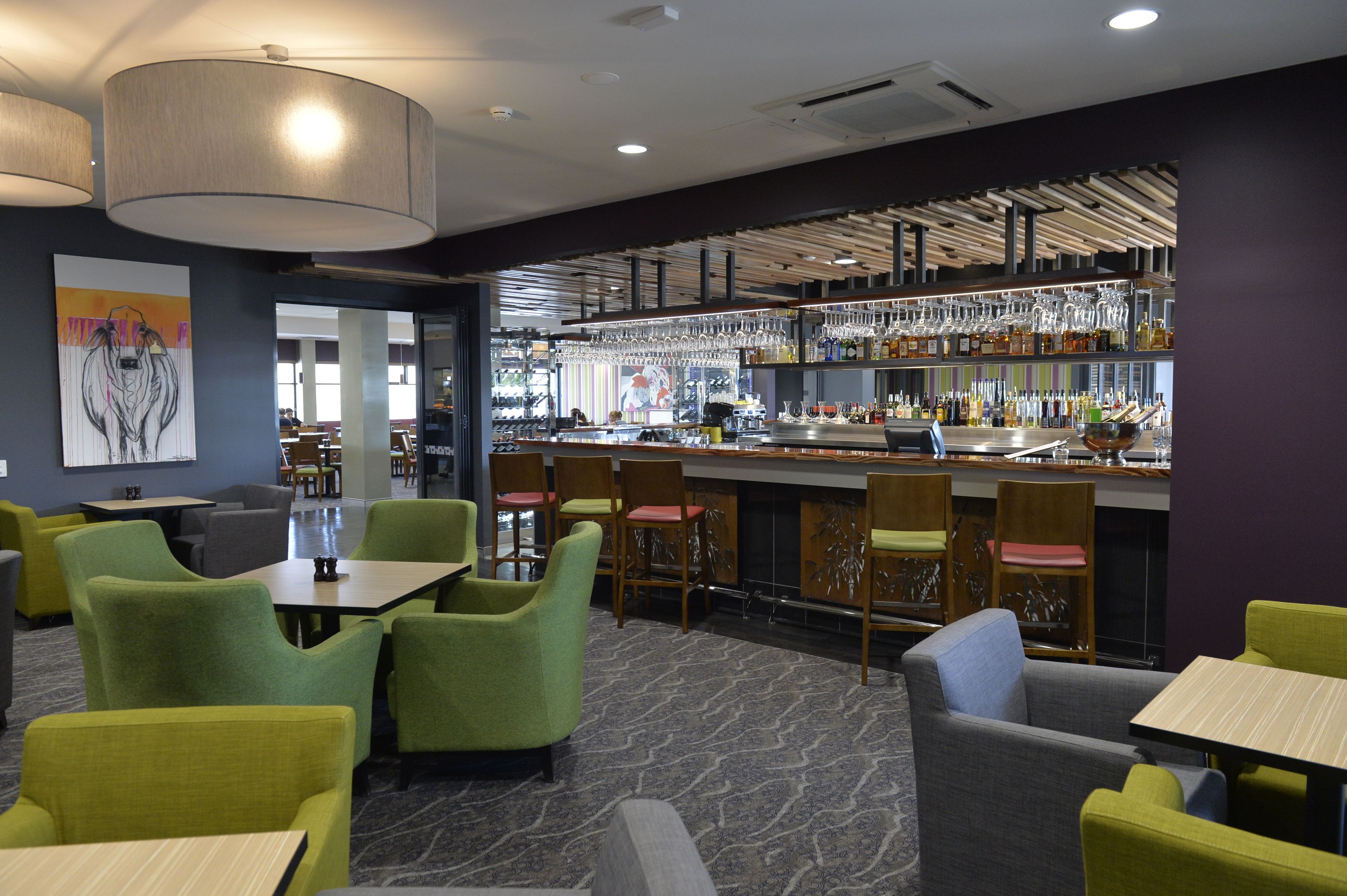 Eine moderne Bar mit Sitzgelegenheiten und einer Theke, die verschiedene Sitzmöglichkeiten und eine gut sortierte Bar bietet.