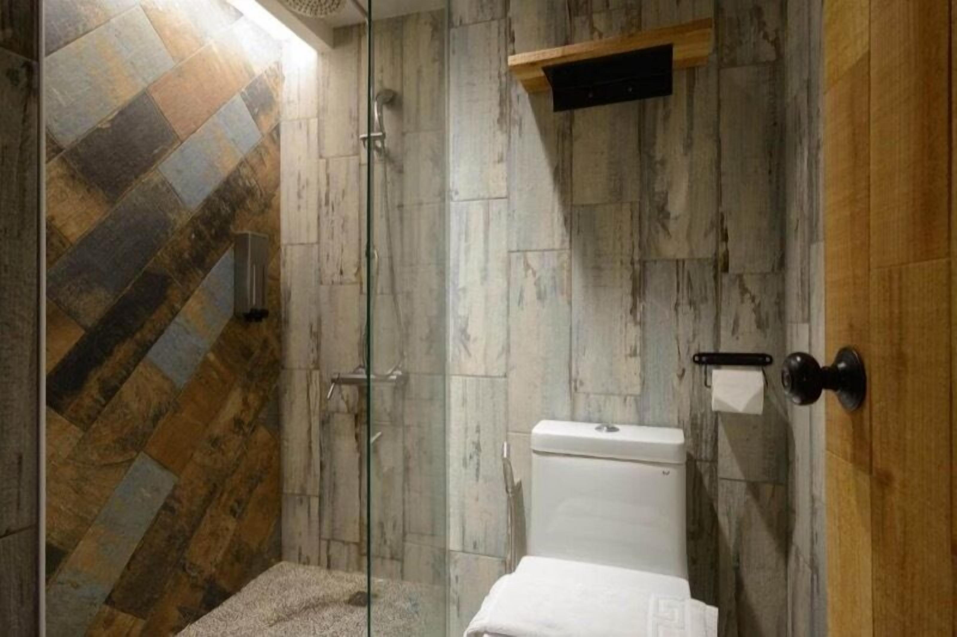 Un baño con ducha, inodoro y toallero.