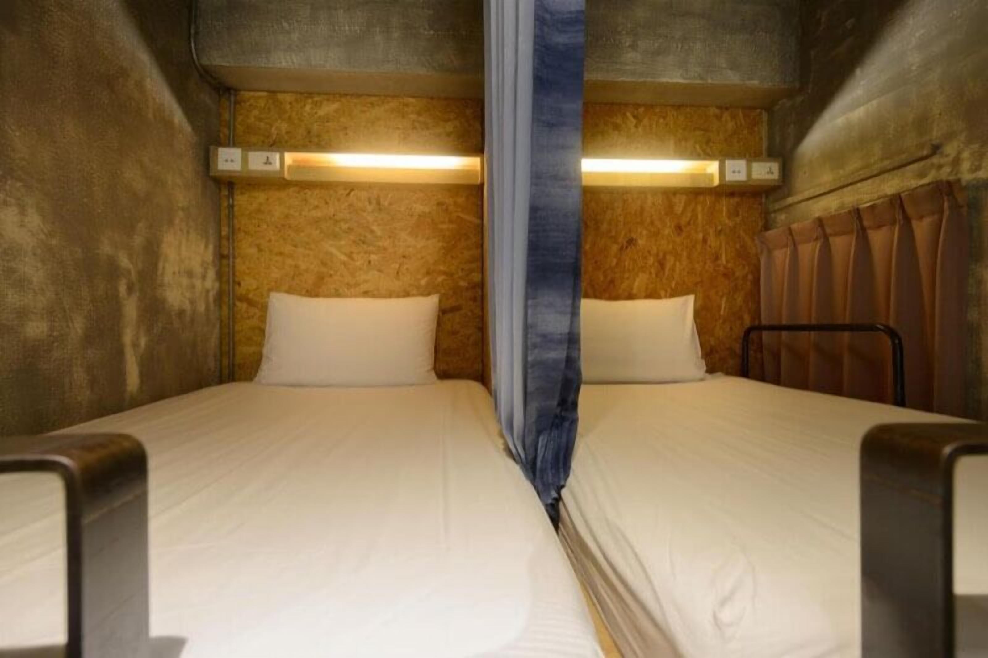 A small, compact room with two beds, wooden walls, and a curtain divider.