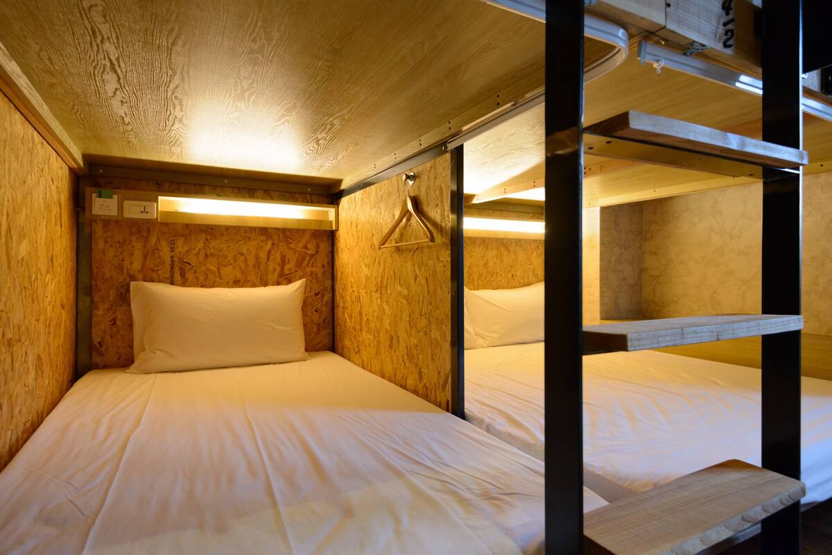 Quarto com beliches, paredes de madeira e um cabide suspenso.