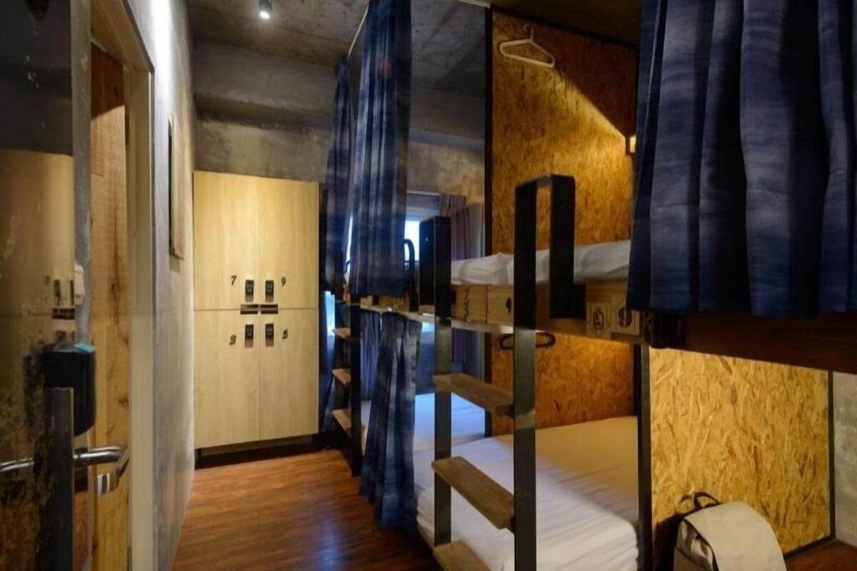 Quarto com beliche, piso de madeira, guarda-roupa e cabideiro.