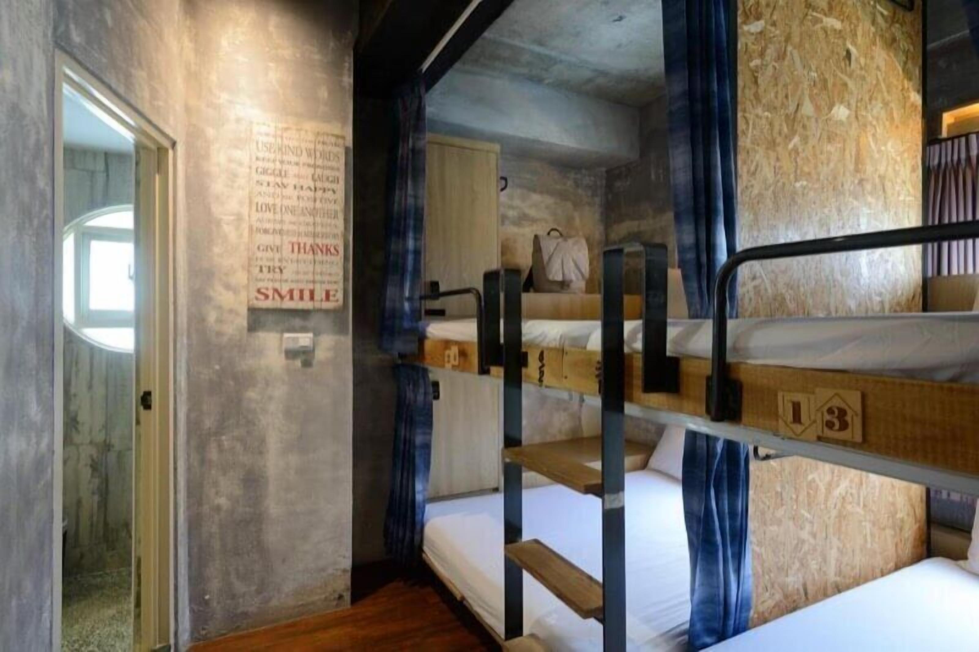 A bunk bed room with a poster on the wall, a door, and a window.