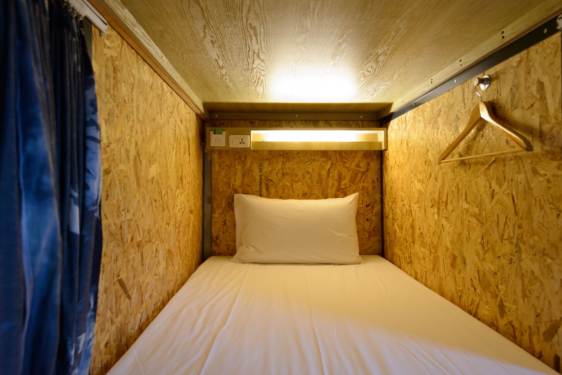 A small, single-bed room with wooden walls and a simple bed.
