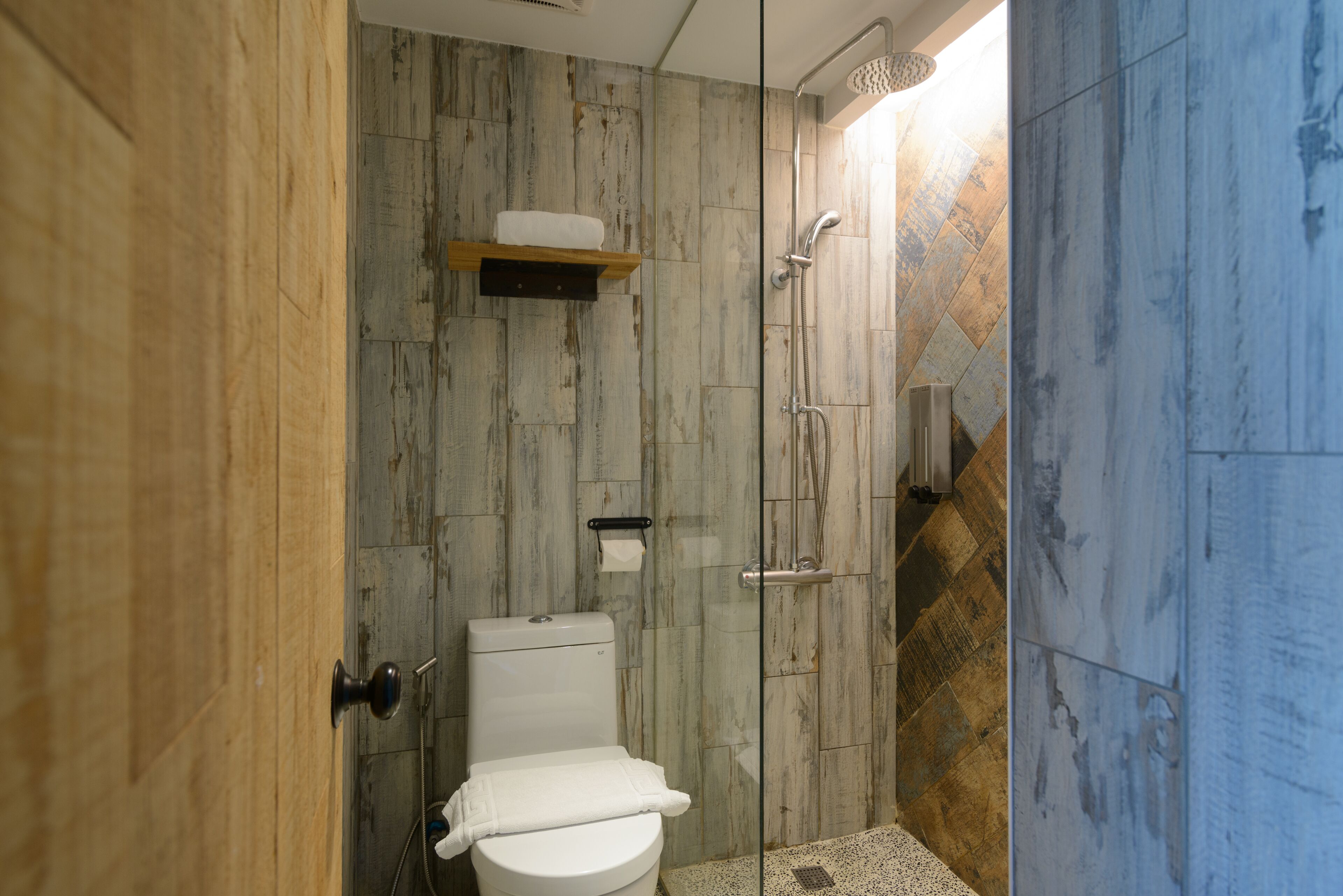 A bathroom with a toilet, a shower, and a towel rack.