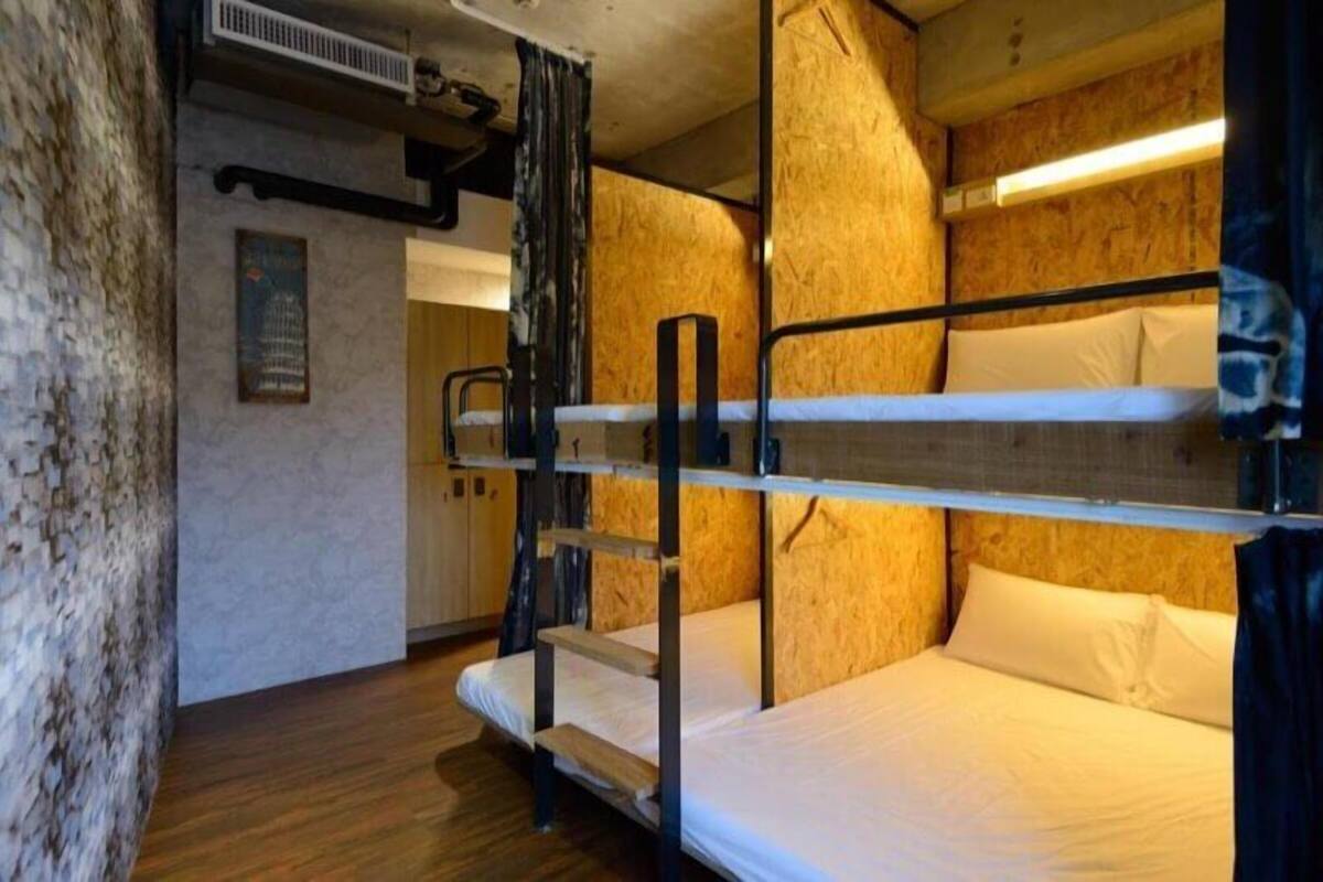 Quarto com beliches, paredes de madeira e escada de metal.