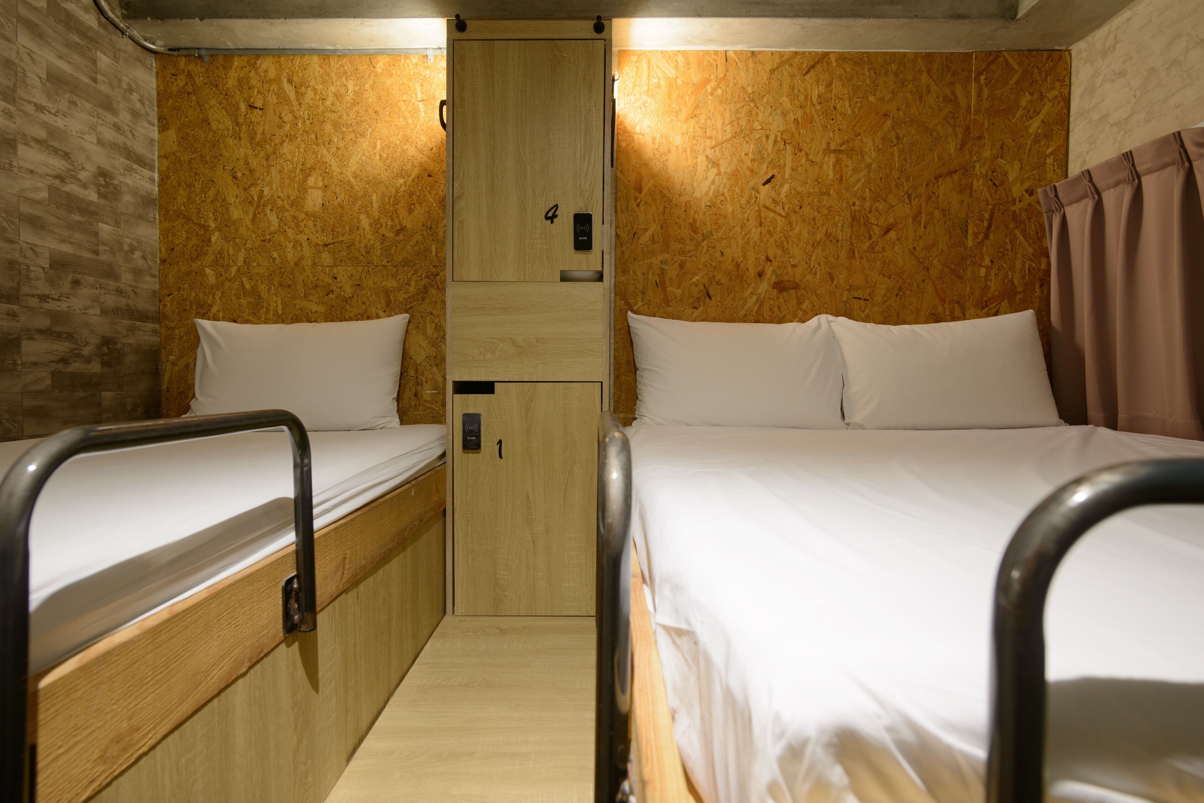 Una cabaña pequeña y compacta, con un solo cuarto, dos camas, un kitchenette y una pared de madera.
