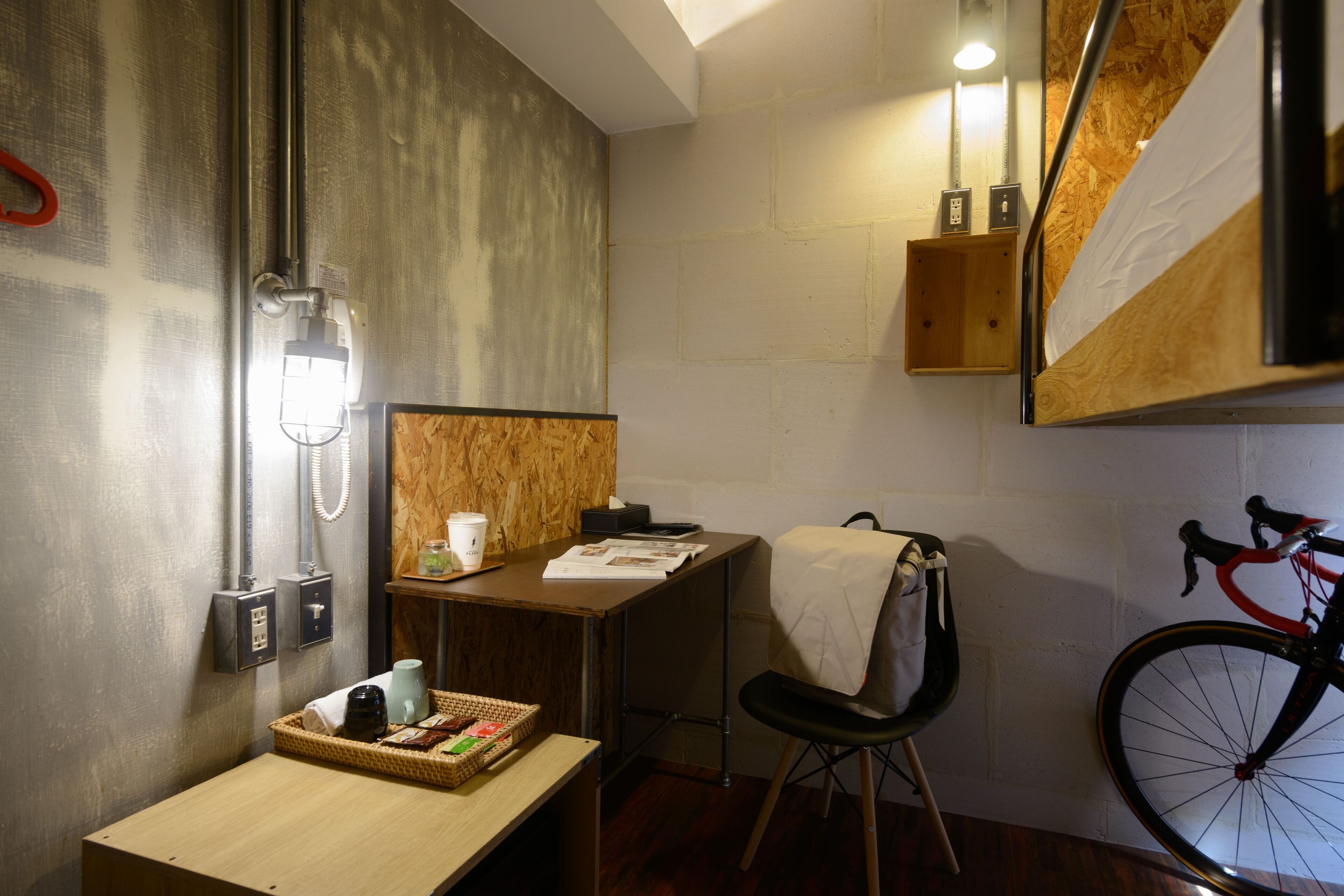 A compact room with a wooden desk, a chair, a bicycle, and a mirror.
