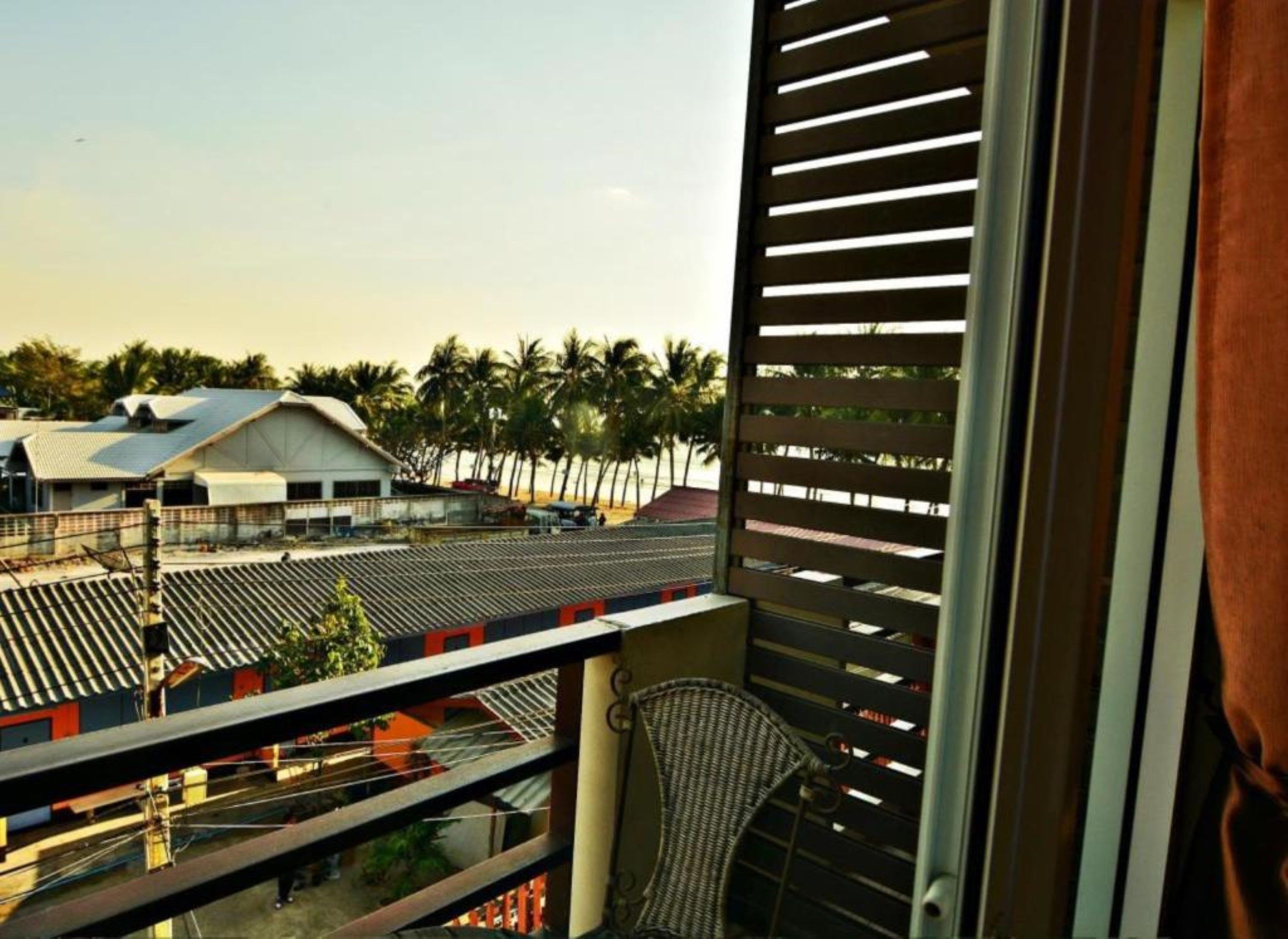 A balcony with a view of a building and palm trees.