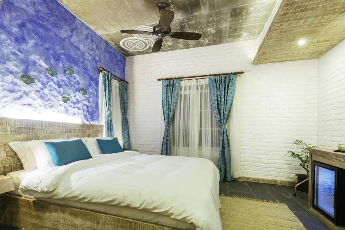 A bedroom with a bed, a ceiling fan, a TV, and a window with curtains.