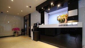 Un comptoir d’accueil avec une pancarte indiquant « RENSEIGNEMENTS » et un arrangement floral.