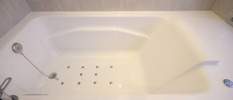 Eine weiße Badewanne mit Duschkopf und Armaturen.
