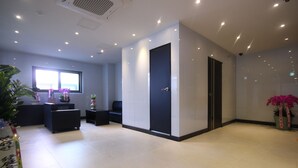 Un hall d’hôtel moderne avec un comptoir d’accueil, un espace salon et une grande fenêtre.