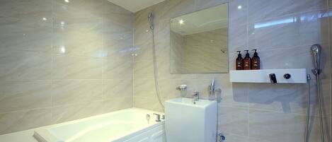 Un baño moderno con bañera, lavabo, espejo y ducha.