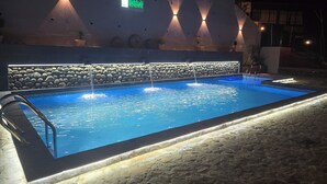 A swimming pool with a stone wall, a sign reading 'Balthali,' and a night-time setting. - Balthali Village Resort (Balthali)