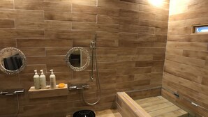 Een moderne badkamer met houten wandtegels, een ronde spiegel, een handdouche en een inbouwbad.