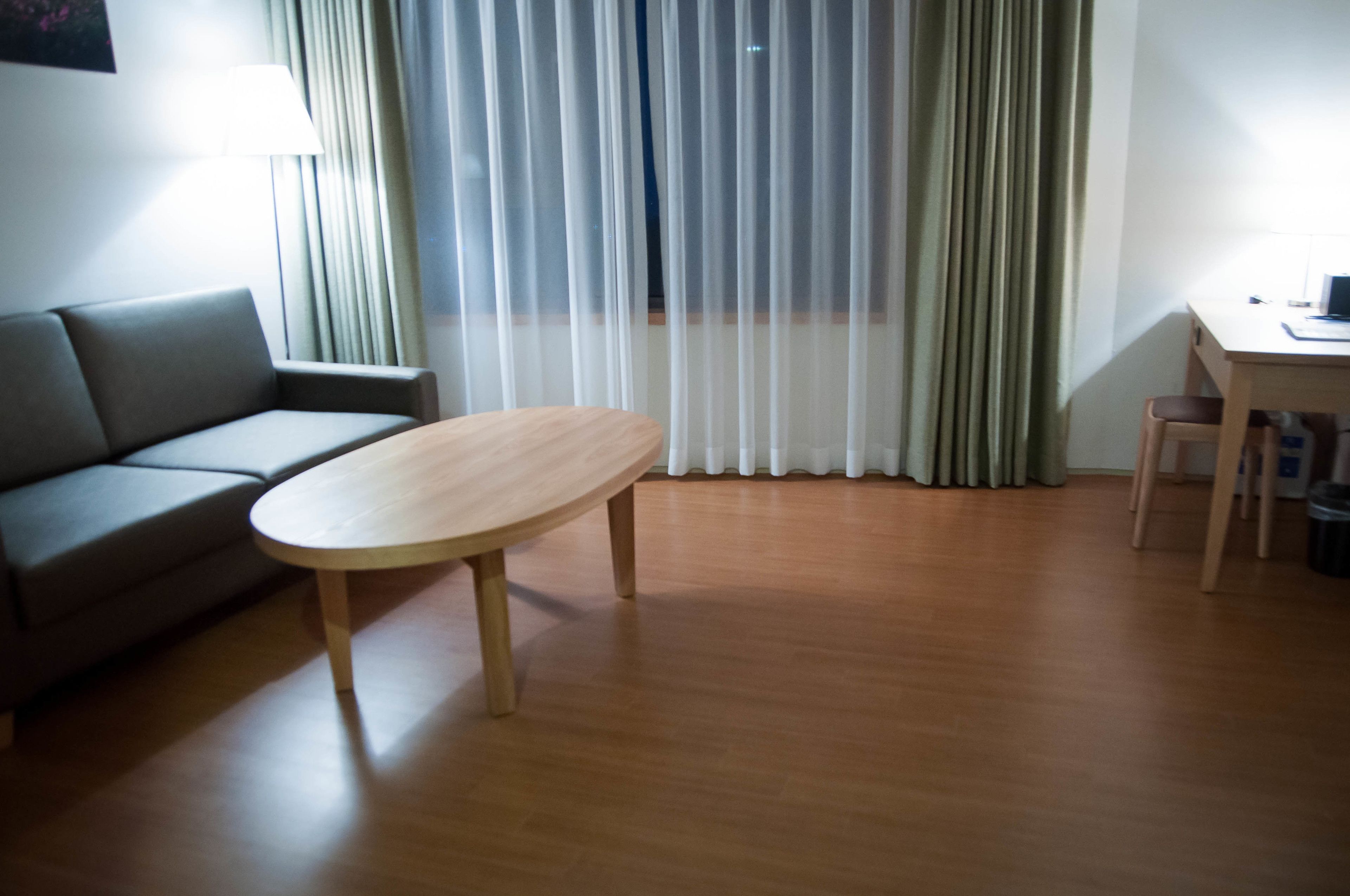 A room with a wooden floor, a sofa, a table, and a desk.