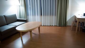 A room with a wooden floor, a sofa, a table, and a desk.