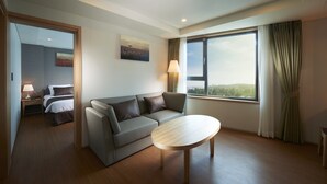 Une chambre d’hôtel moderne, dotée d’un canapé, d’une table ronde et d’une grande fenêtre donnant sur l’extérieur.