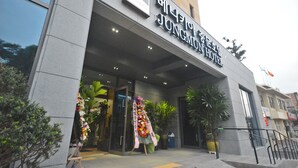 L’extérieur de l’hôtel Jungmuen se distingue par sa façade moderne, son grand hall d’entrée vitré et une composition florale qui agrémente l’entrée.