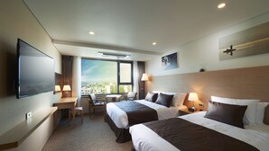 Une chambre d’hôtel avec deux lits, un bureau, une chaise, une télévision et une grande fenêtre donnant sur la ville.