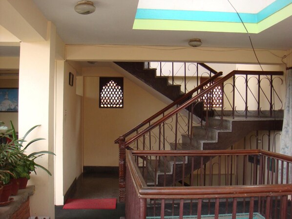 Una escalera con barandillas de madera y una alfombra roja que conduce a un piso superior.