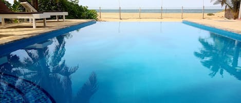 Piscina all'aperto, una piscina a sfioro, lettini