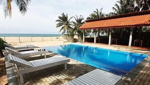 A pool area with lounge chairs, a covered seating area, and a view of the beach. - Wellé Wadiya (Kudawa)
