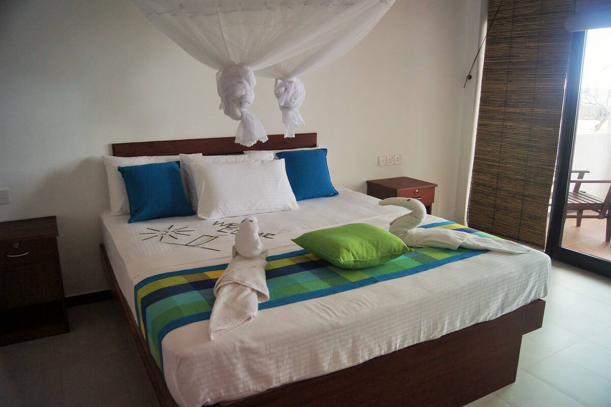 A hotel room with a bed, a nightstand, a window with a view, and a curtain.