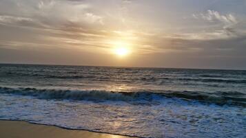 A beach with waves and a sunset.