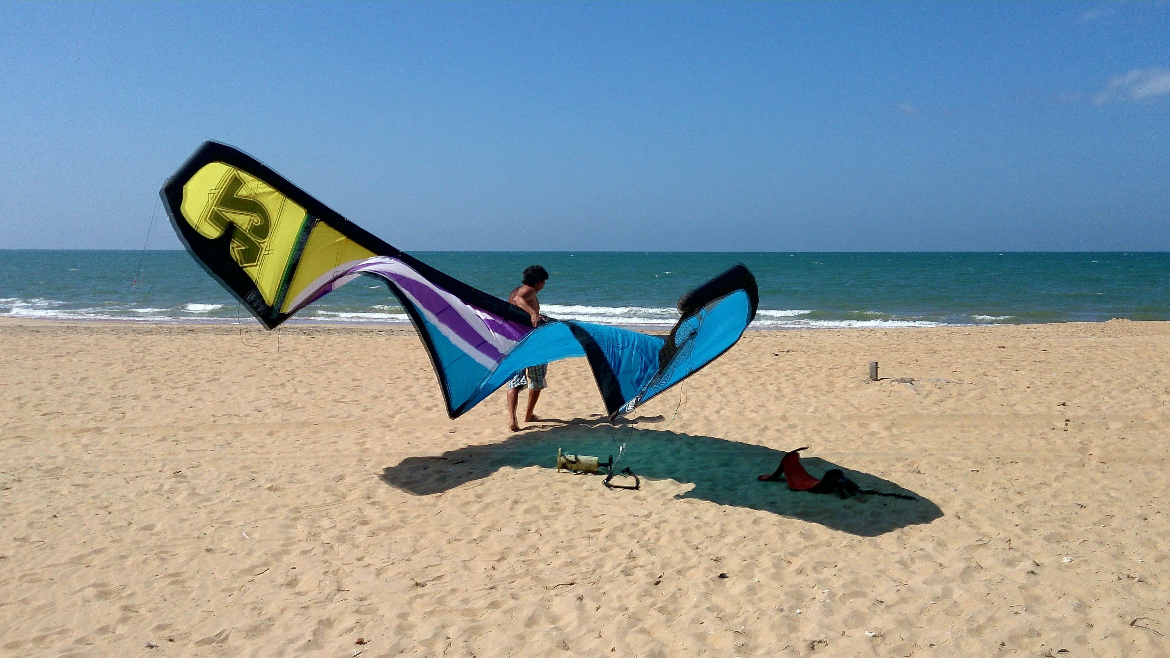 Una playa con una persona sosteniendo una cometa grande.