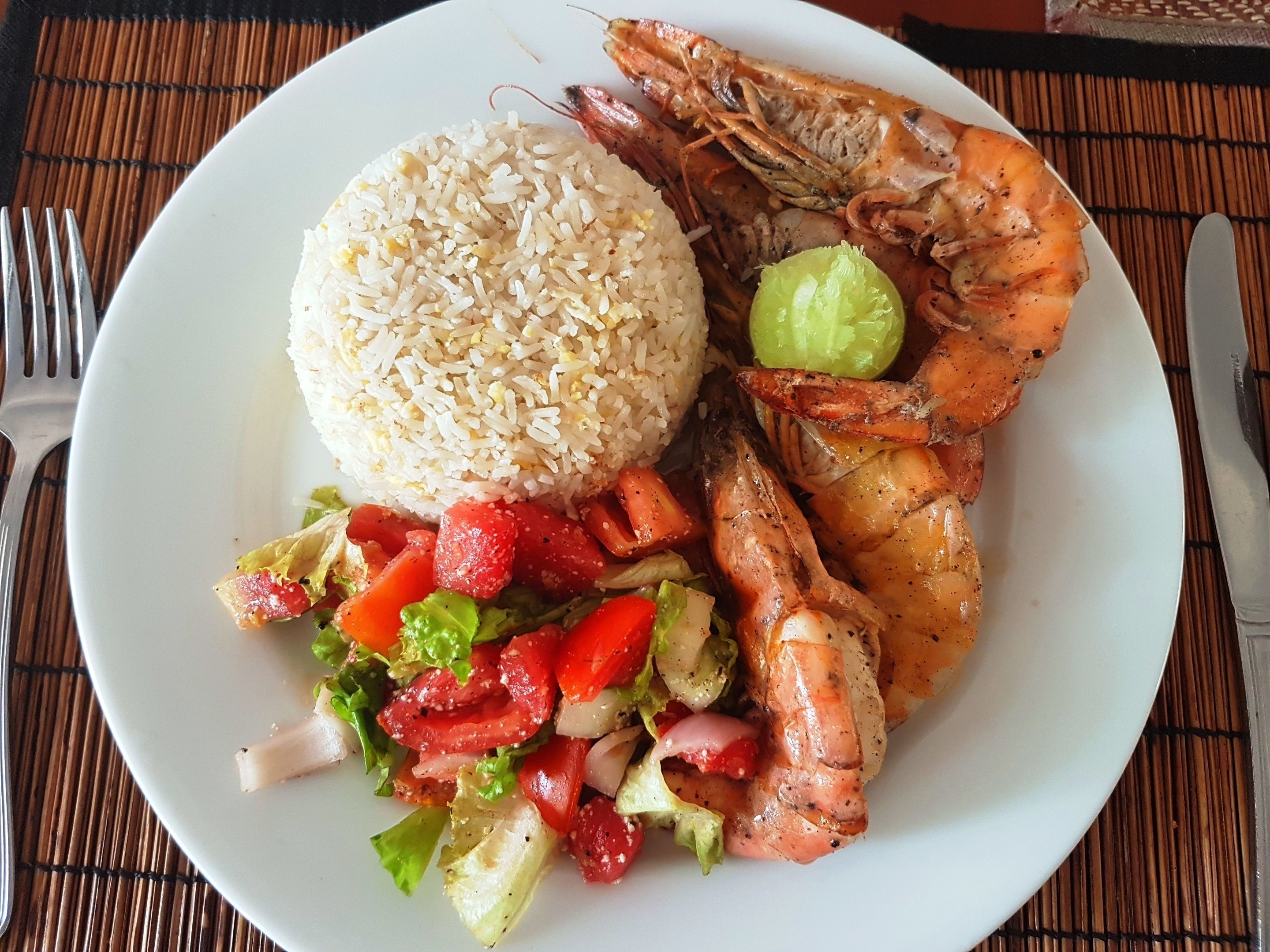 A plate with rice, shrimp, and a salad.