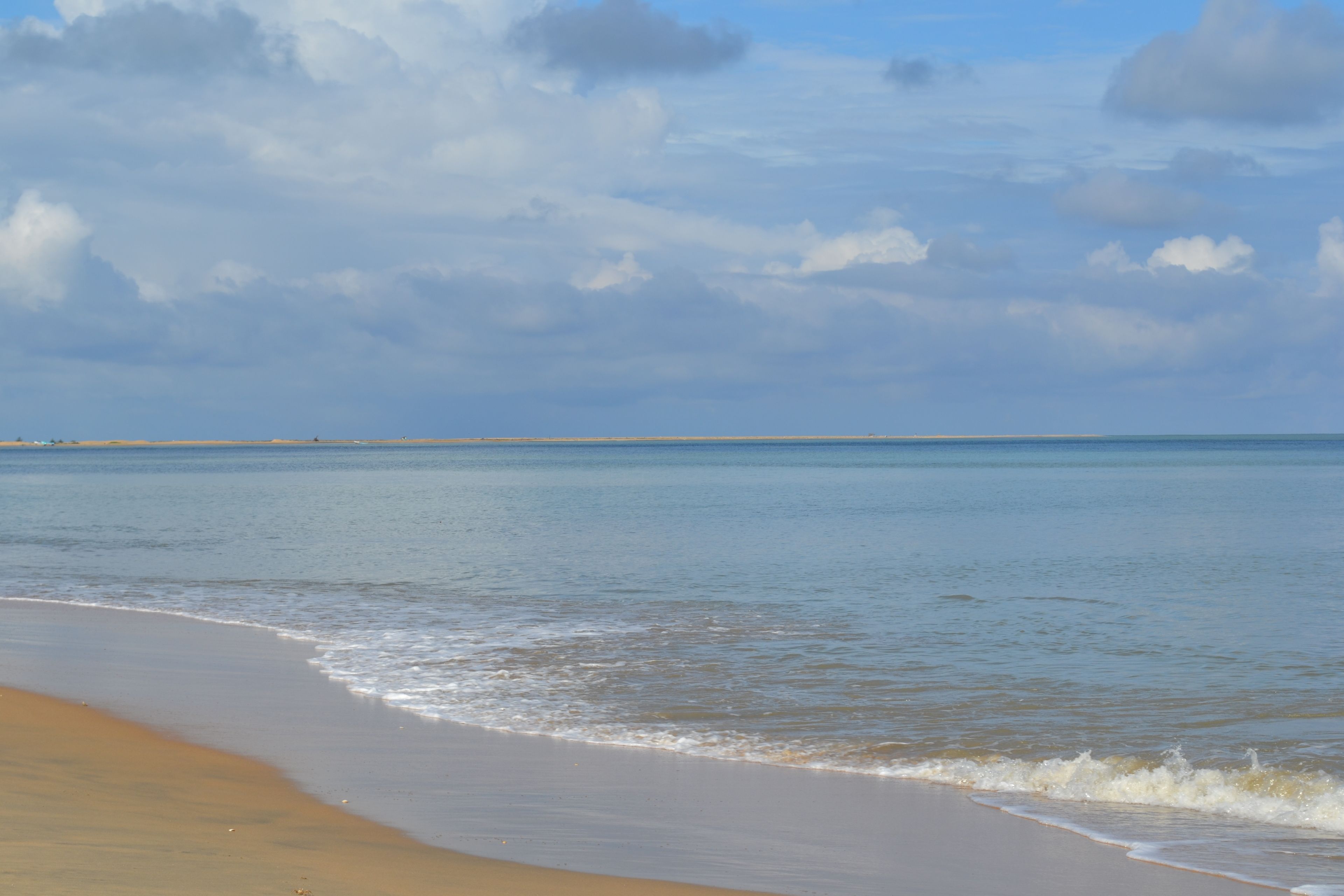 Una playa con una amplia orilla arenosa y olas suaves.