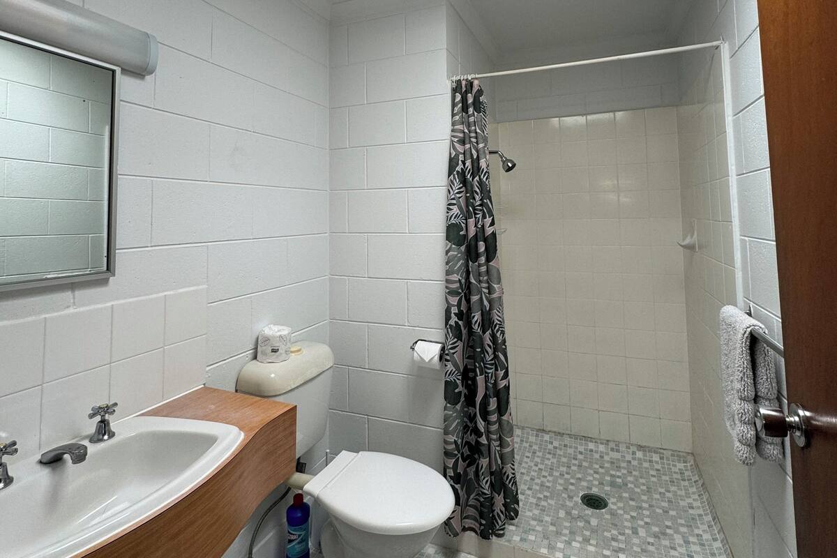 Un baño pequeño con tragaluz, inodoro, lavamanos y ducha.