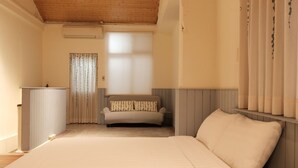 Ein Schlafzimmer mit einem großen Bett, einer Couch, einem Heizkörper und einem Fenster mit Vorhängen.