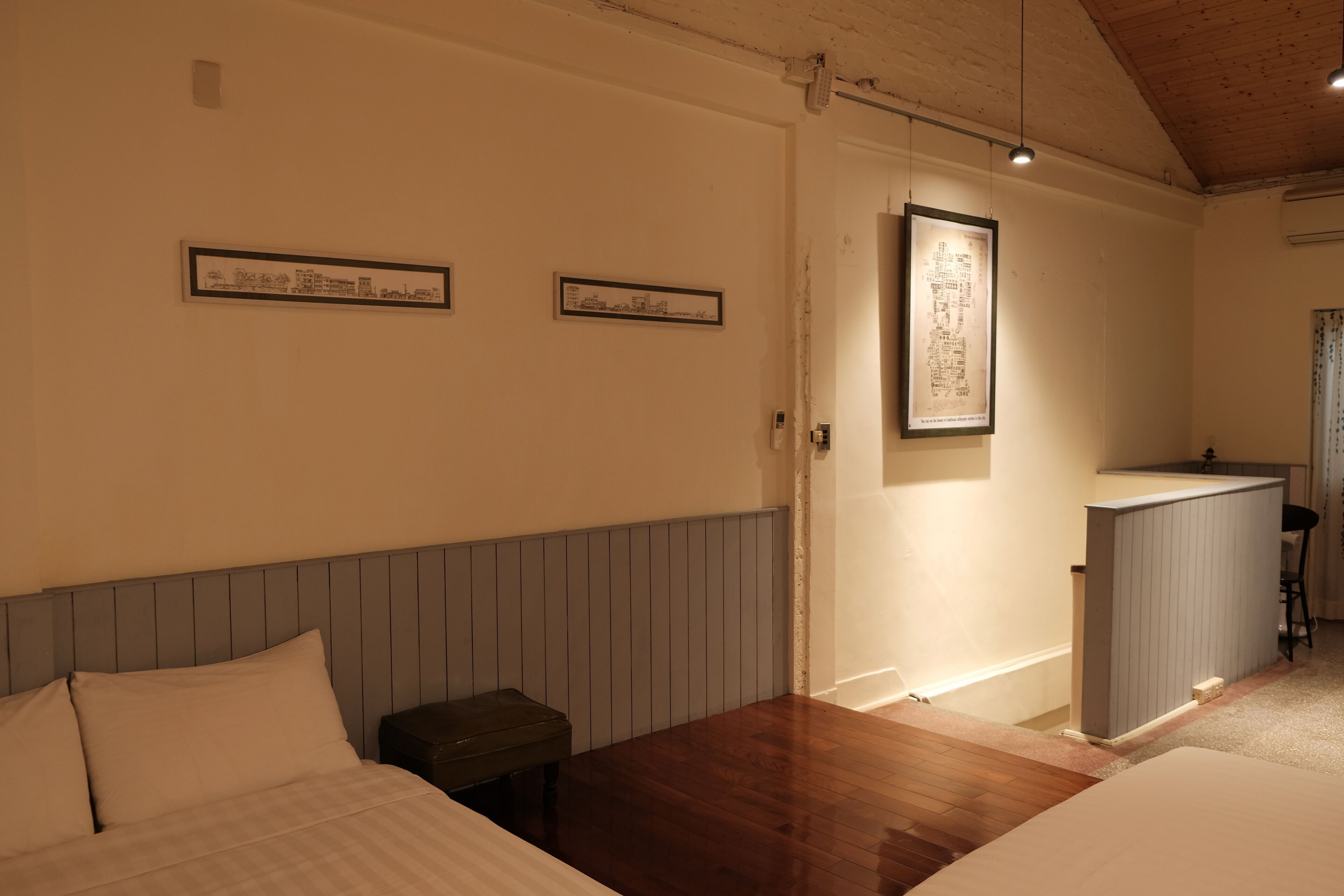 A bedroom with a wooden headboard, a small bedside table, and a framed map on the wall.