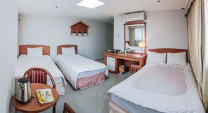 Et hotelværelse med to enkeltsenge, et skrivebord med stol, et lille bord med elkedel og te, og en fastgjort varmeovn på væggen.