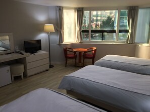 A hotel room with two beds, a desk with a TV, a chair, a lamp, and a window with curtains. - Busan Central Hotel (Busan)