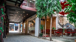 An indoor courtyard with a brick wall, potted plants, and wooden chairs. - Vien Ngoc Xanh 1 Hotel (Ho Chi Minh City)