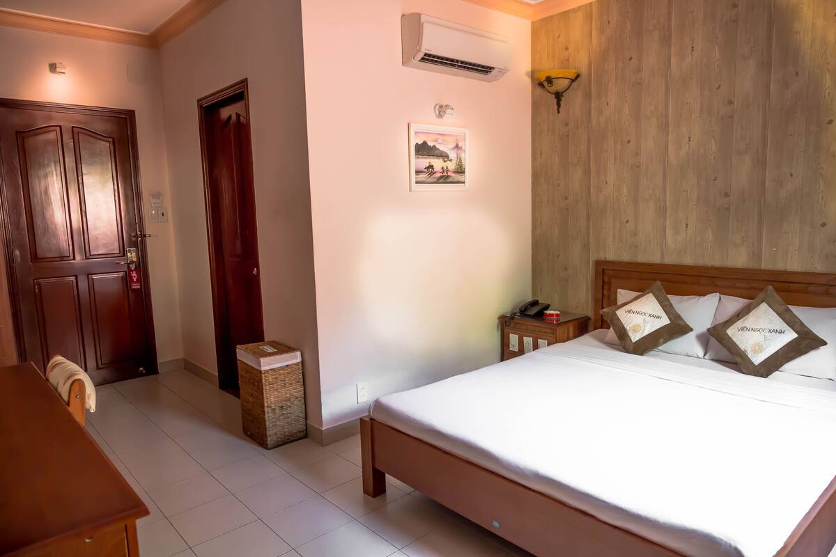 Ein Schlafzimmer mit einem hölzernen Bett, einem Nachttisch, einem Schreibtisch und einer Tür.