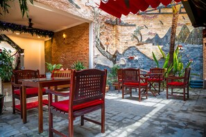 A patio area with wooden furniture and a mural on the wall.